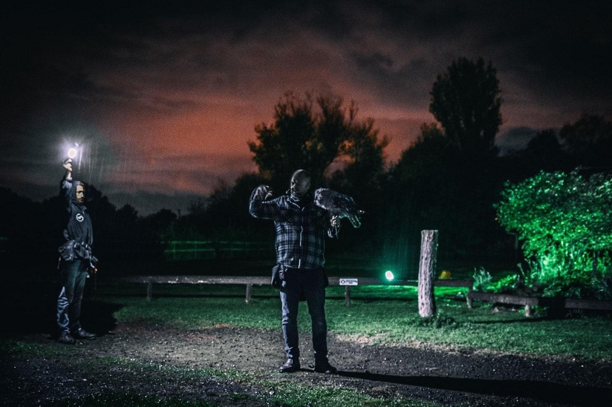 A man holding an owl in the moonlight