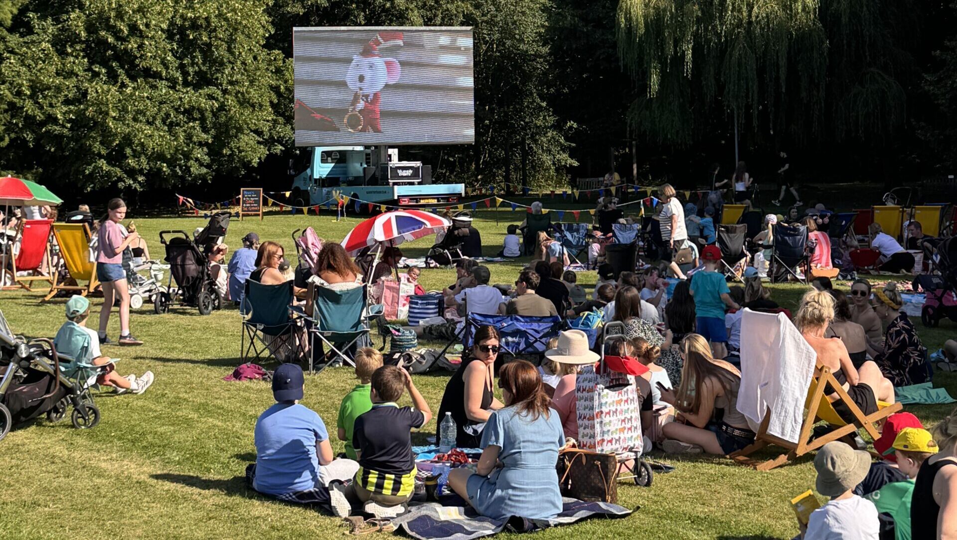 Families sat outside watching an outdoor cinema screen
